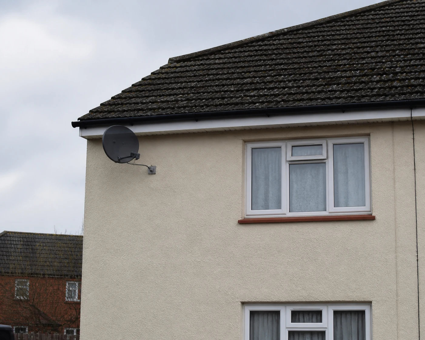 Existing satellite dish on a house wall needing adjustment